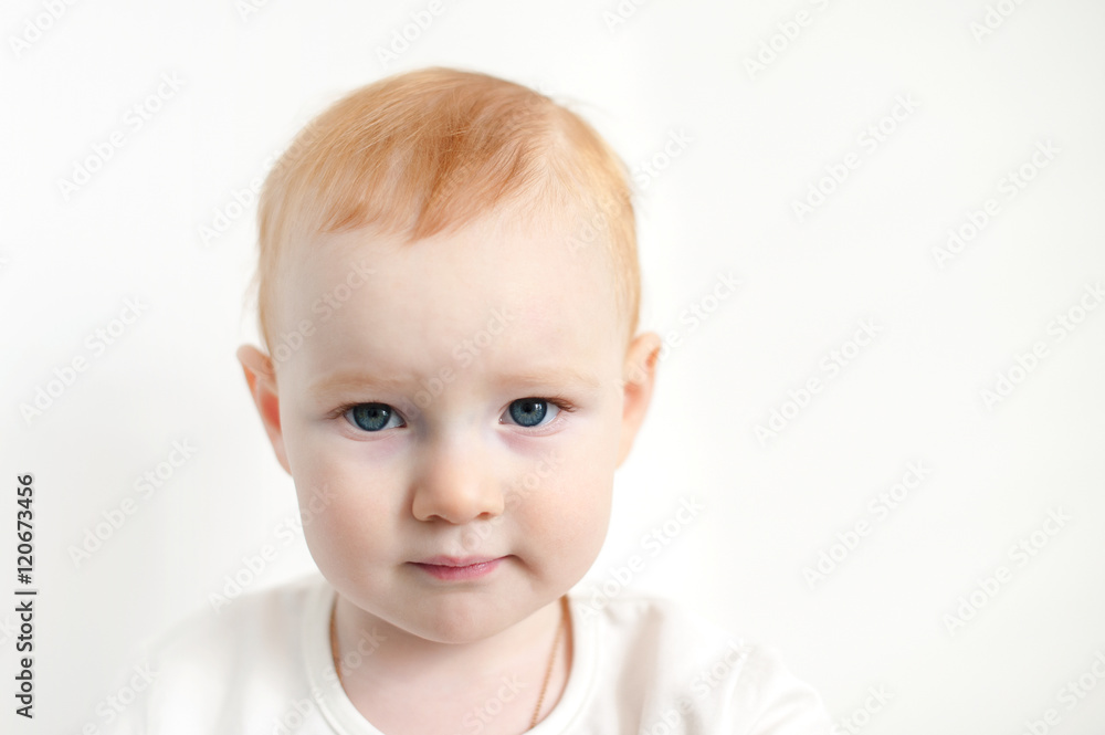 Beautiful red-haired child against a white wall with copyspace