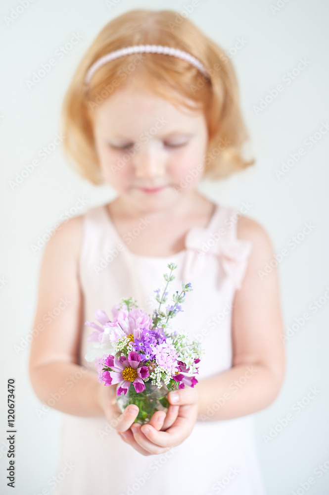 Beautiful red-haired child holding a bouquet of summer flowers Beautiful red-haired child holding a bouquet of summer flowers
