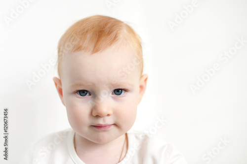Beautiful red-haired child against a white wall with copyspace