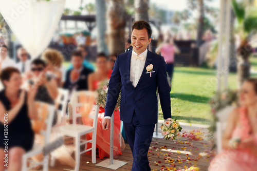 Stylish happy smiling groom on the luxury outdoor wedding ceremo photo