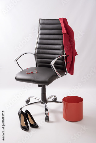 An executive black leather chair with a red coat waste bin,shoes and glasses