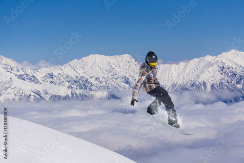 Snowboarder jumping in snowy winter mountains