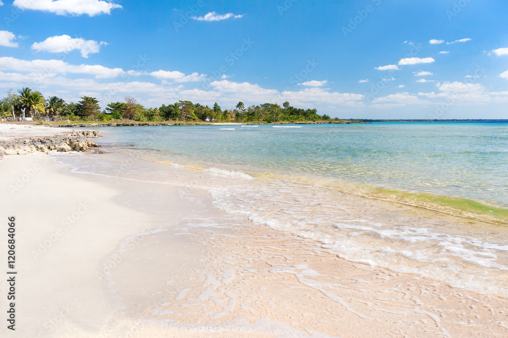 Soft wave of the sea on the sandy beach. Blue sky, white sand, palm trees and azure sea. Cuba, Varadero, Caribbean sea.
