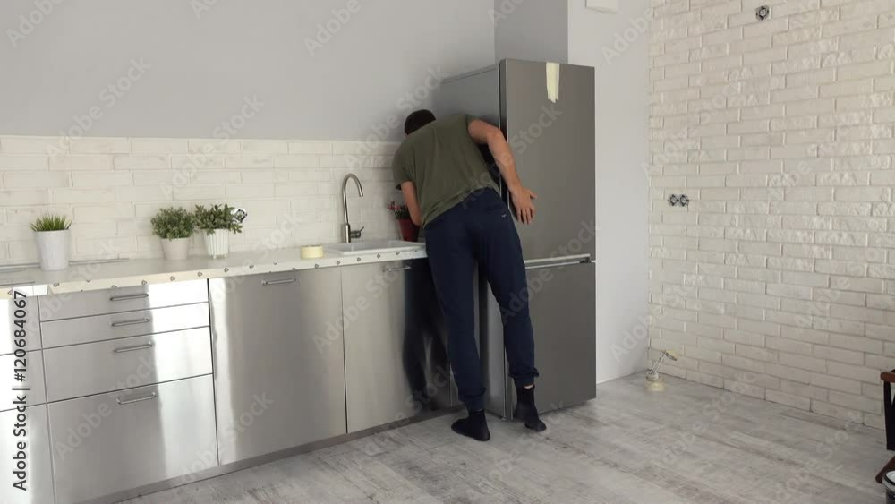 Young man having problems with fitting new fridge to furniture at his new home
Young man having problems with fitting new fridge to furniture at his new home