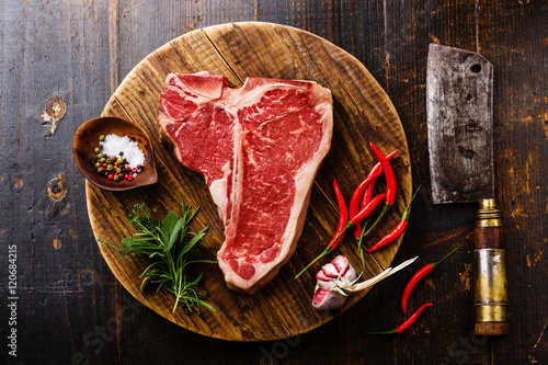 Raw fresh meat T-bone steak, seasoning and Butcher cleaver on ch photo