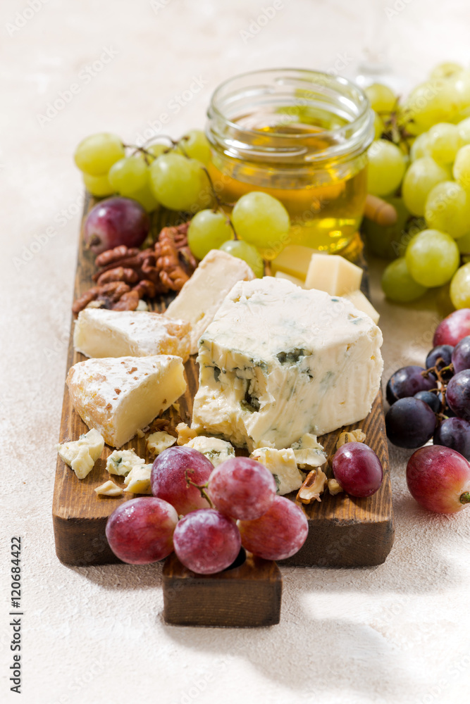 cheeseboard, fresh grapes and honey on a white background