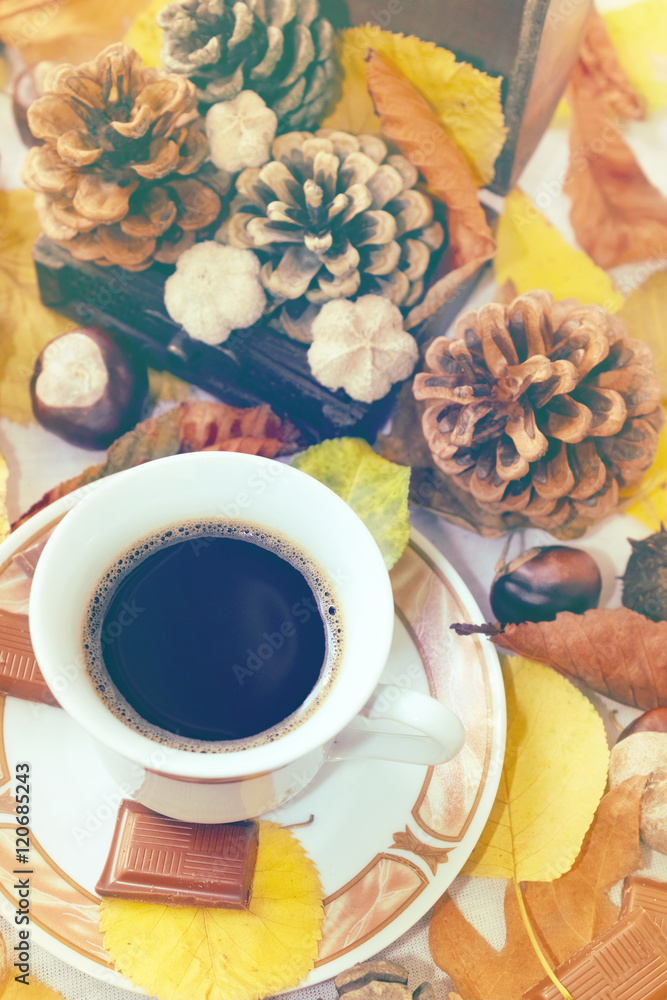 Fototapeta premium Autumn Cup of black coffee, chestnuts, pine cones, chocolate and autumn leaves. Autumn background. Autumn scene. Coffee and autumn leaves. Fall background. Autumn colors.