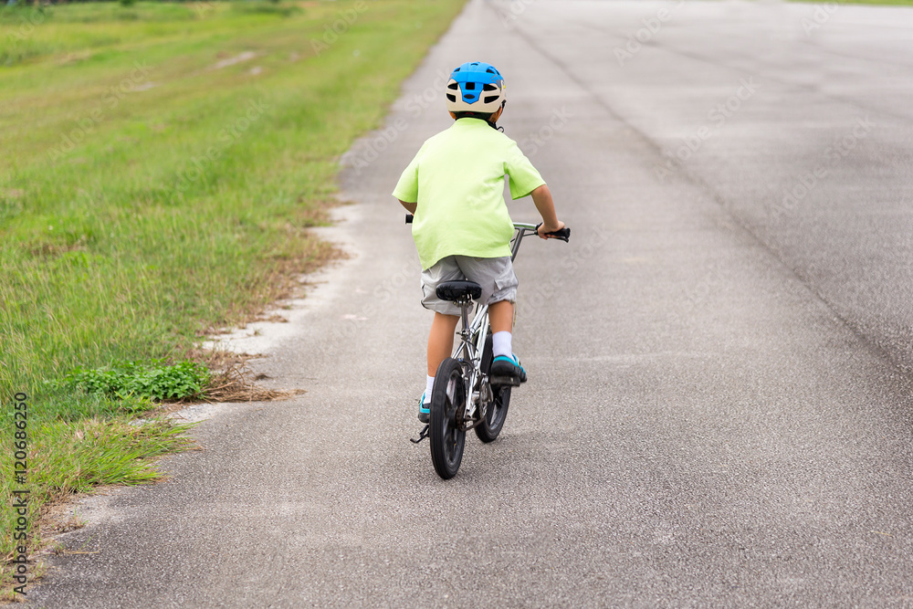 Obraz premium Asian cute boy riding on his bicycle on the road.