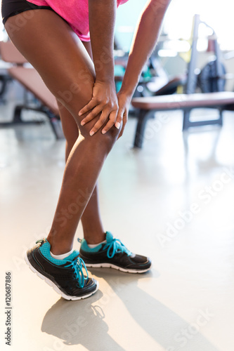 Portrait of a muscle fitness woman reaching for her knee in pain