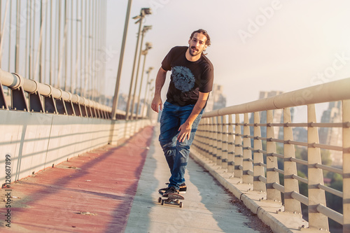Skateboarder skates over a city bridge. Free ride street skateboarding © guruXOX