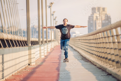 Fototapeta Naklejka Na Ścianę i Meble -  Skateboarder skates over a city bridge. Free ride street skateboarding