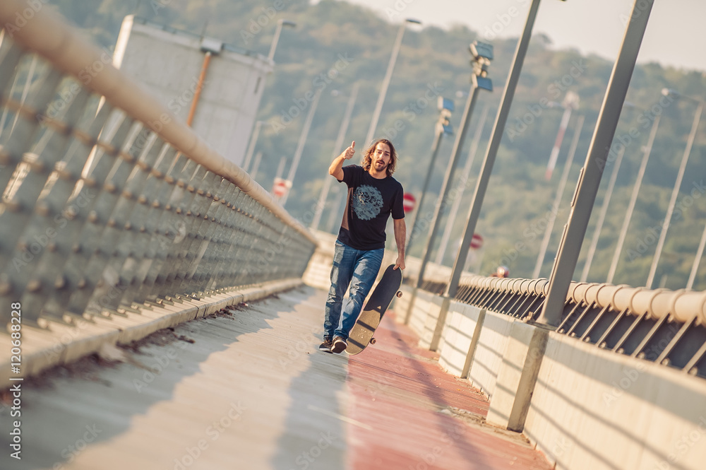 Skateboarder skates over a city bridge. Free ride street skateboarding
