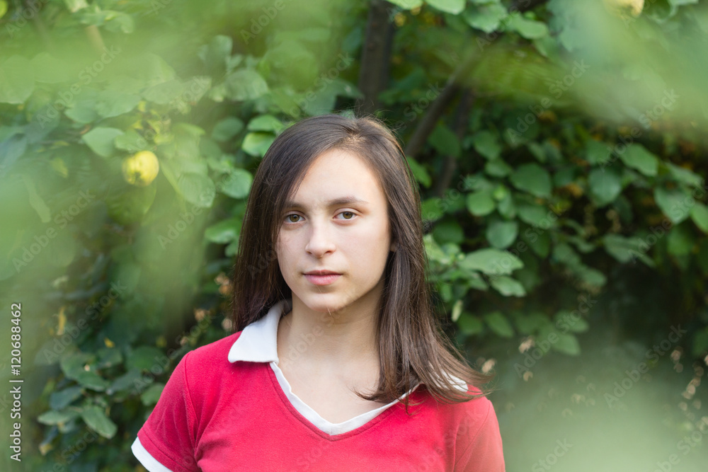 Portrait of teenage girl with dark hair near tree in orchard garden Portrait of teenage girl with dark hair near tree in orchard garden