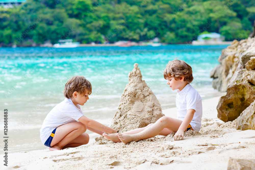 Two kid boys building sand castle on tropical beach Two kid boys building sand castle on tropical beach