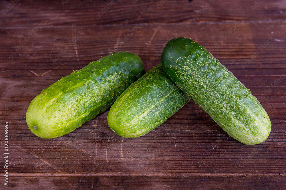 Three cucumbers on a wooden background.. Three cucumbers on a wooden background..