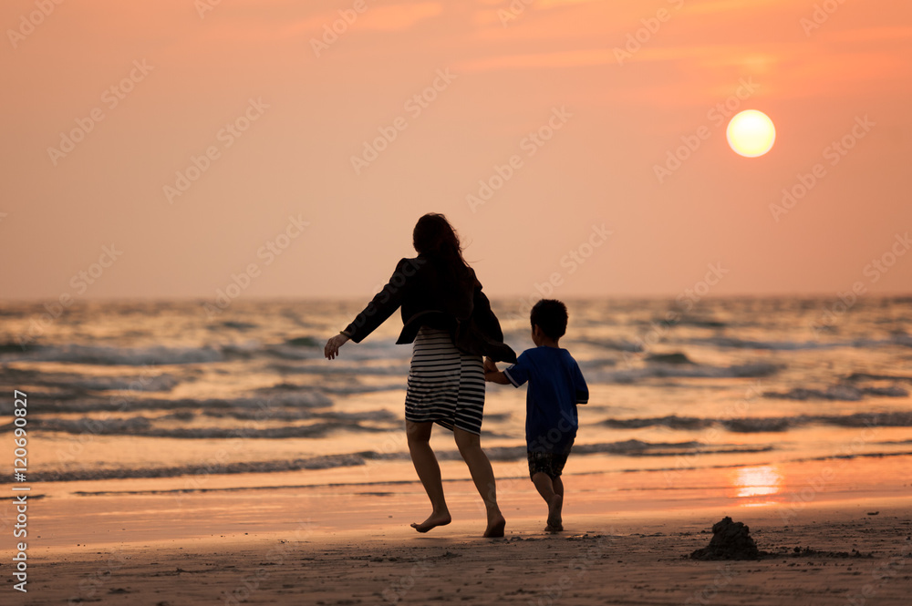 Mother and son on the beach on the beach during sunset