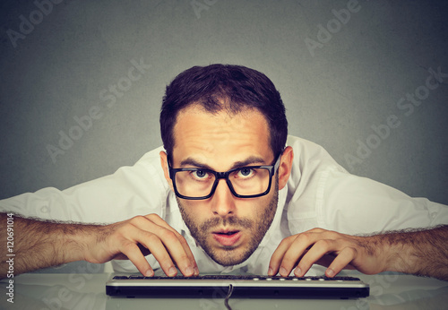 Crazy looking nerdy man typing on the keyboard photo