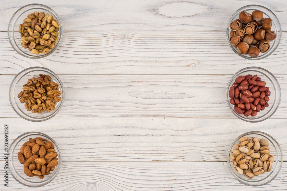 Mix nuts in a glass bowl on the old wooden table. Mix nuts in a glass bowl on the old wooden table.