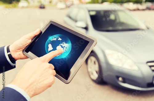 close up of male hands with tablet pc and car