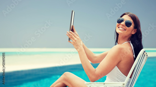 smiling woman with tablet pc sunbathing on beach