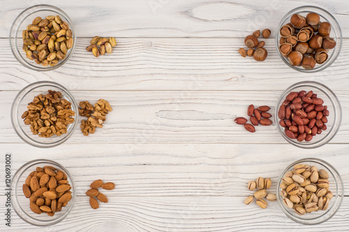 Mix nuts in a glass bowl on the old wooden table.