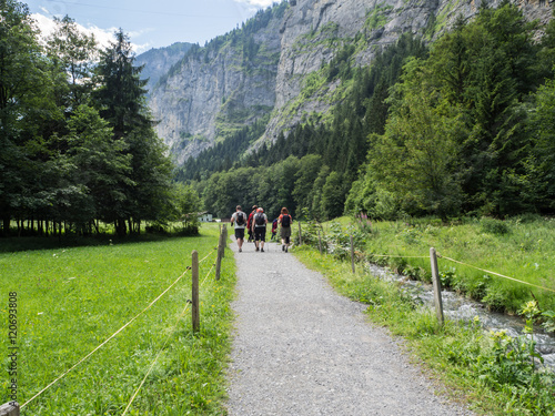 Paisaje verde con acantilados al fondo, arboles verdes y un camino para pasear con mucho espacio en Lauterbrunnen, Suiza, viajando en verano de 2016