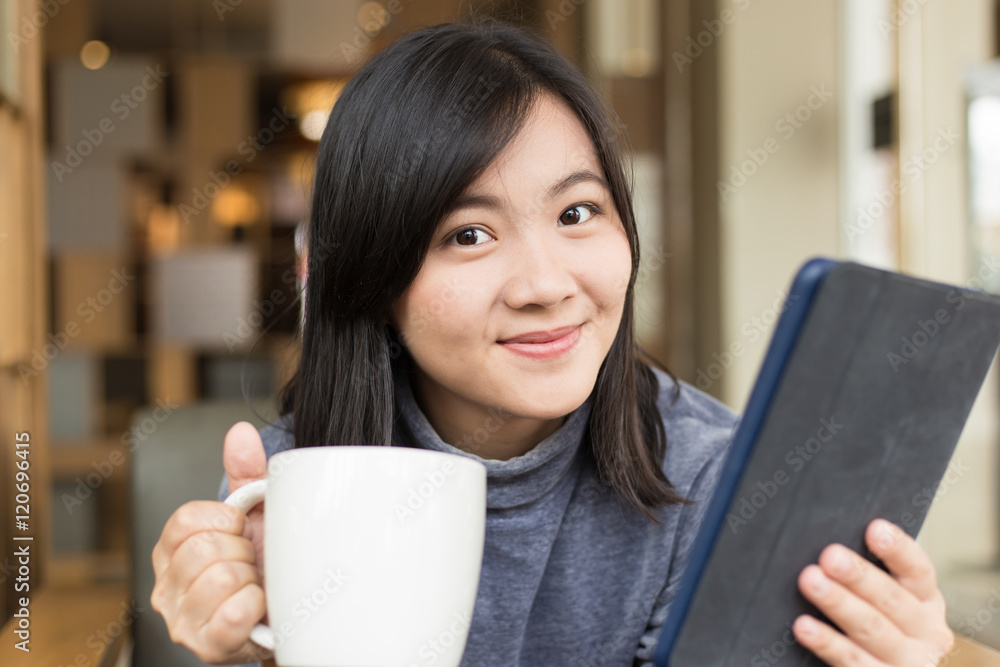 Woman drinking coffee / tea and using tablet in a coffee shop Woman drinking coffee / tea and using tablet in a coffee shop