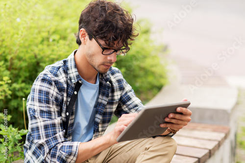 man with tablet pc sitting on city street bench