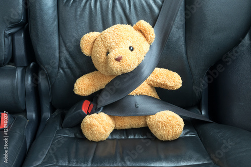 Teddy bear fastened in the back seat of a car
