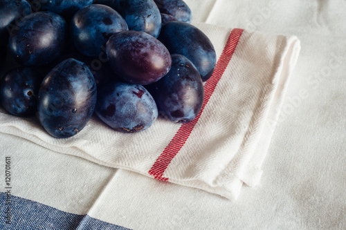 Ripe plums on textile napkins and rural tablecloth