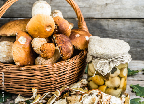 Autumnal mushrooms preserves, boletus marinated in jar and dry mushroom on rustic background