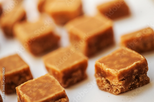 Caramel candies on brown background. Salted caramel pieces and s