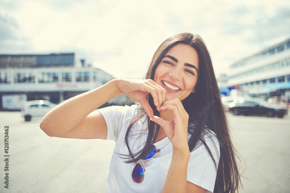 Laughing young woman making a heart gesture Laughing young woman making a heart gesture