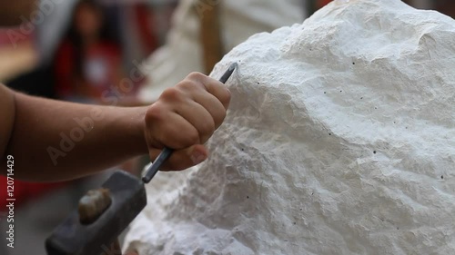 Young student at work learning craftsman profession in art class, working with hammer to carving stone statue from white stone