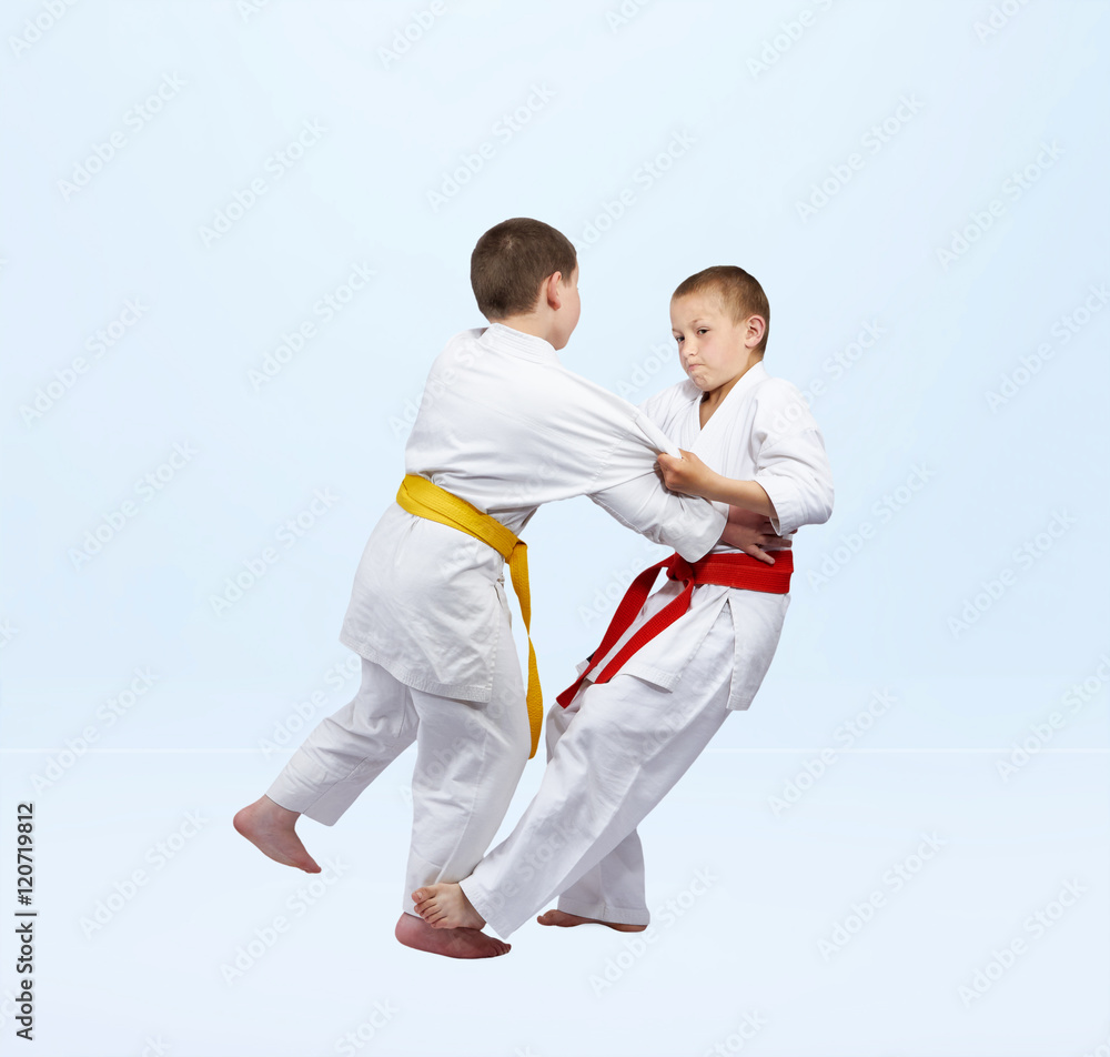 Boys in judogi are training grip for throw