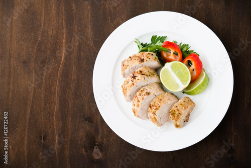 Sliced lime pork tenderloin on dark wooden background top view. Space for text. Healthy food.