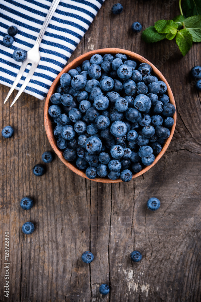 Full bowl of fresh ripe blueberries on old wooden board Full bowl of fresh ripe blueberries on old wooden board