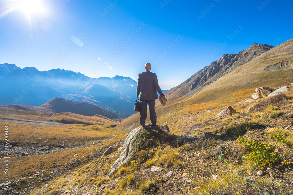 a man in a suit on a background of mountains in the summer, panorama, landscape, businessman