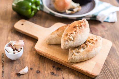 Hot pies with mushrooms on cutting board, vegetable calzone