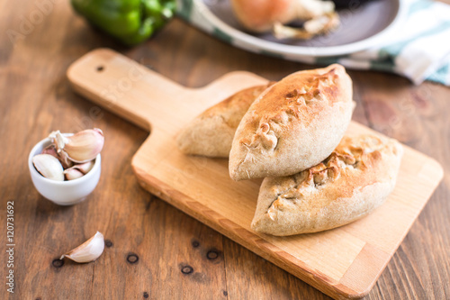 Hot pies with mushrooms on cutting board, vegetable calzone