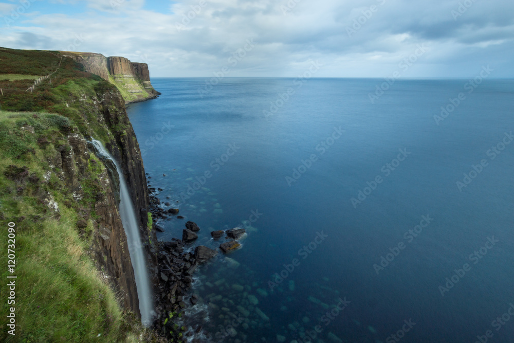 Beautiful waterfall ends up in the sea. Scotland´s coastline with wonderful cliffs.