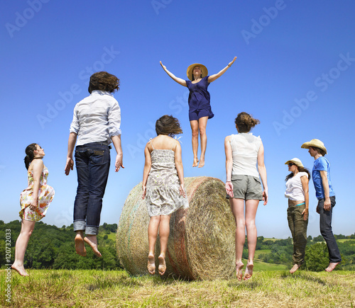 Young people jumping around hay