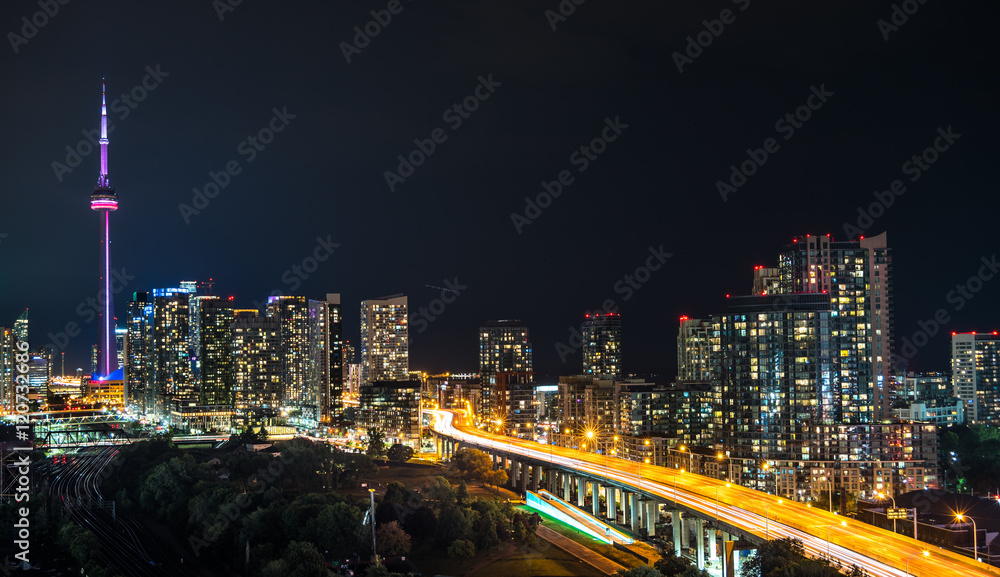 Fototapeta premium Glowing light streaks from traffic along the Gardiner Expressway on a hot & muggy summer night in Lakeside Toronto, Canada.