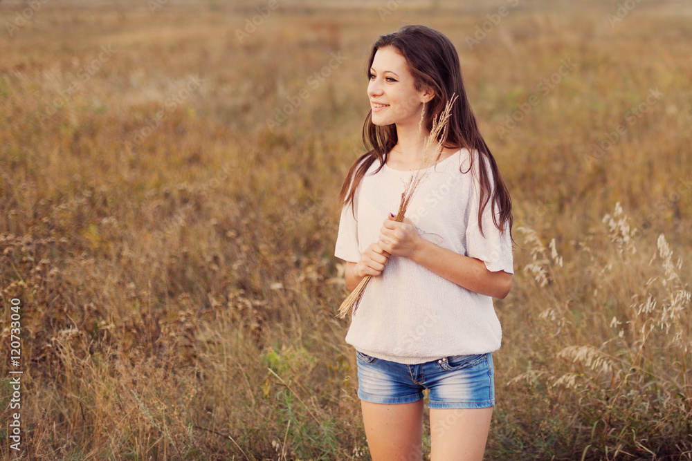 Young girl with long brown hair holds a bundle of ears