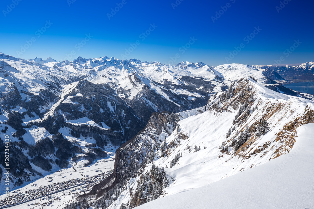 View to Skiers on the ski slopes and Swiss Alps covered by fresh new snow seen from Hoch-Ybrig ski resort, Central Switzerland