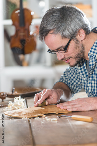 Craftman luthier working on the creation of a violin at workshop