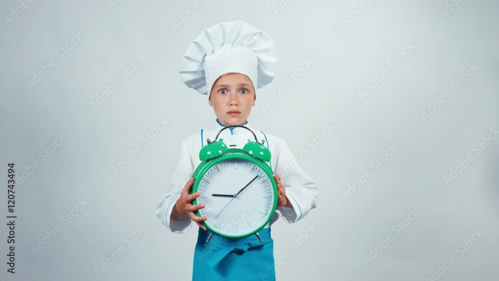 Alarm clock ringing. Little chef cook holds big alarm clock standing on white background looking at camera Alarm clock ringing. Little chef cook holds big alarm clock standing on white background looking at camera