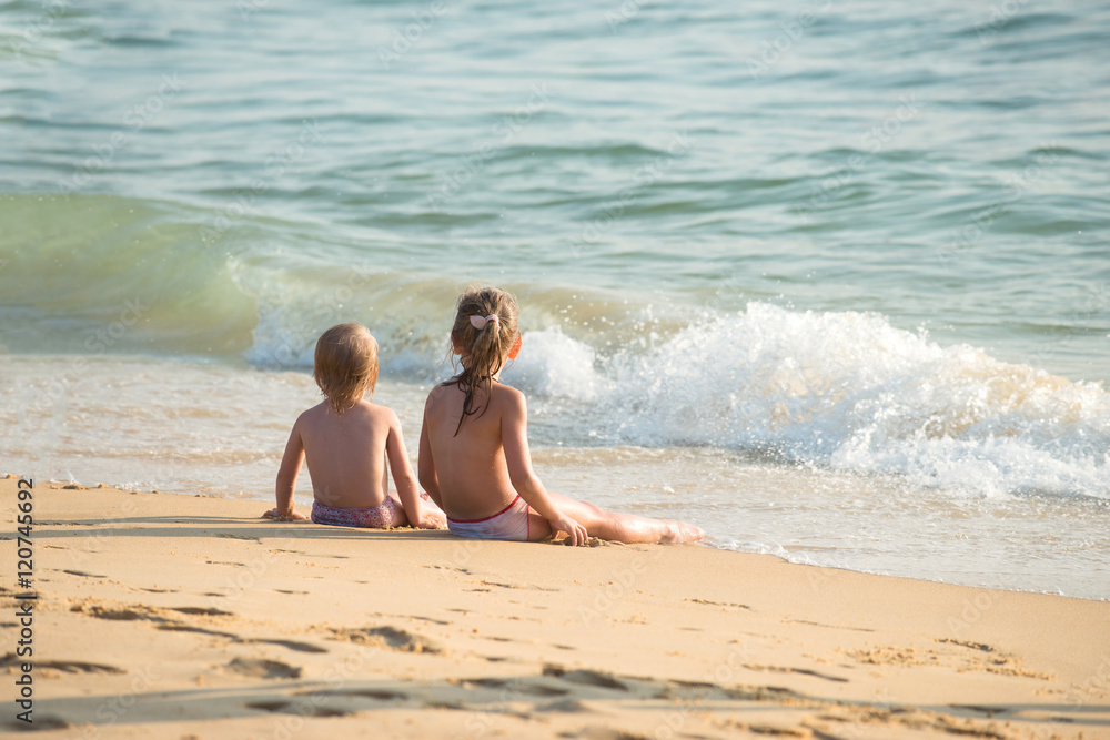 Little boy and girl sitting on the sand, sitting together in the sand looking at the sea, Blurred background, Film simulation Little boy and girl sitting on the sand, sitting together in the sand looking at the sea, Blurred background, Film simulation