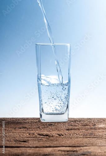 Pouring water on glass on wood