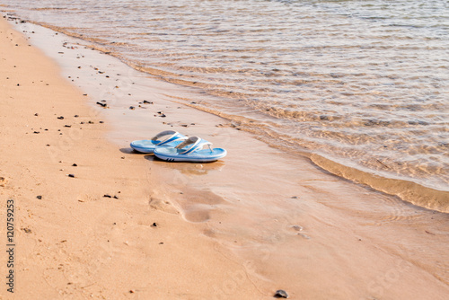 Beach shoes on a sandy beach in front of the sea